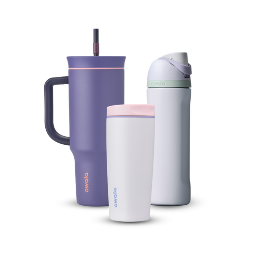 Owala All Day Bundle showing three bottles — a deep purple 40oz Tumbler with side handle, peach pink accent ring, and dark purple straw, a small white insulated cup with pink accent ring, and a white FreeSip with mint green accent band, lavender flip cap, and matching lavender carry loop