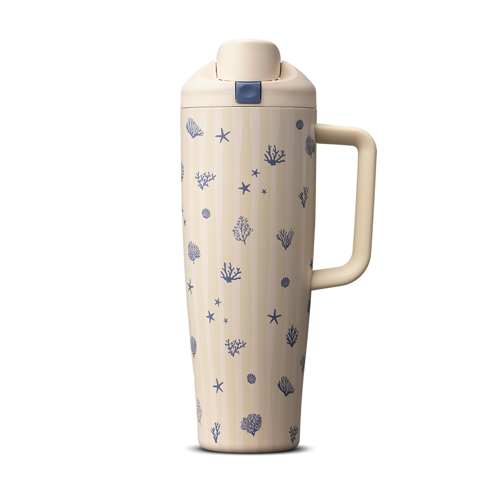 Owala Birthday Bash Coral Cabana 30oz FreeSip Tumbler; cream body with subtle vertical stripes scattered with small navy blue seashells, starfish, coral, and sea urchin illustrations, matching cream flip cap, lid, and side handle