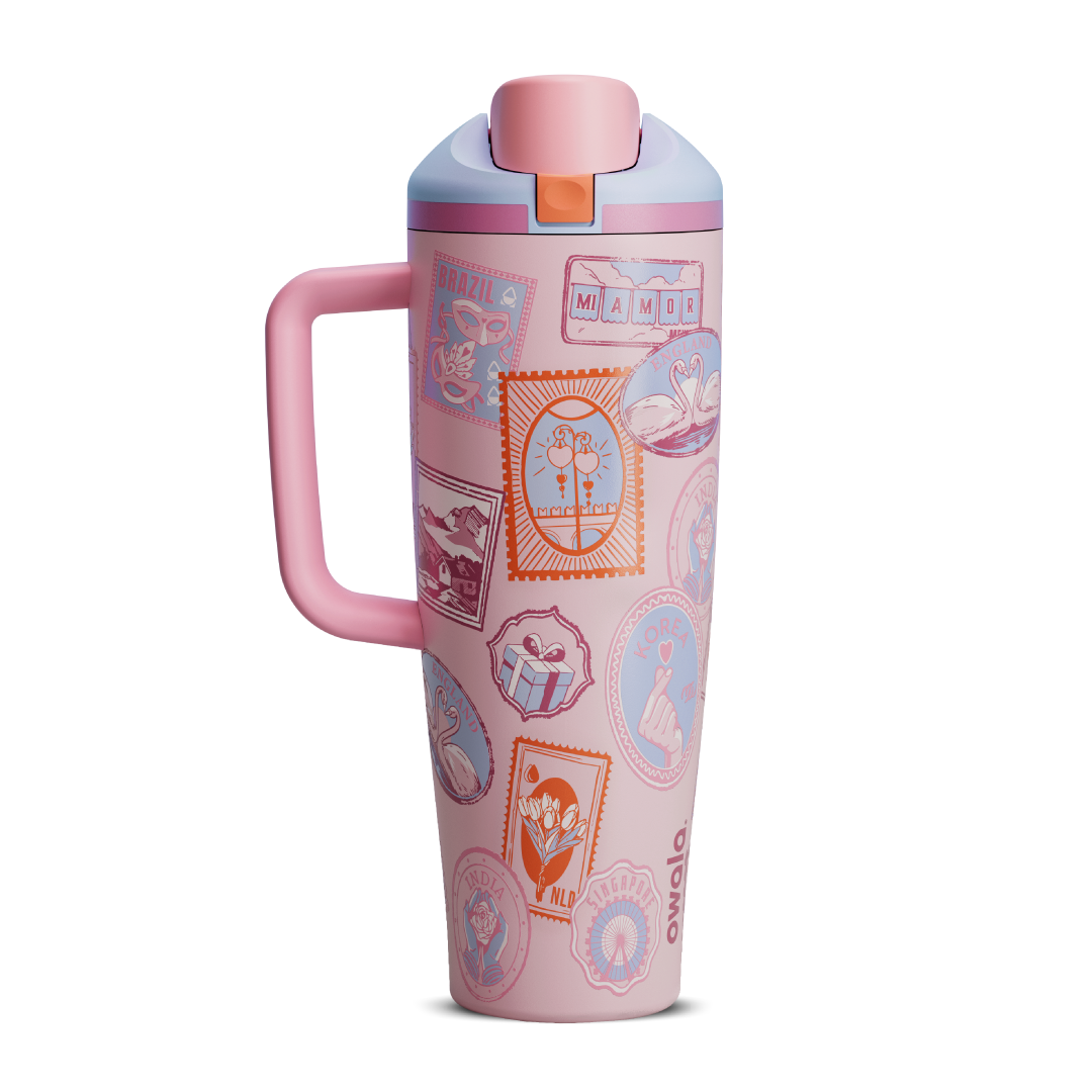 FreeSip Tumbler 40oz in Sending Love, soft blush pink body covered in whimsical illustrated stamp-like patches featuring animals, flowers, and travel motifs, with matching pink handle, pink flip cap, and lavender lid