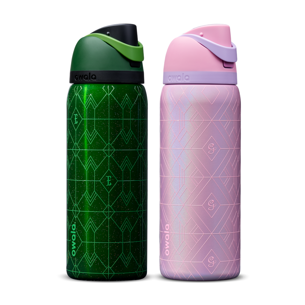 Owala Wicked 32oz FreeSip bundle showing two bottles side by side — deep emerald green Elphaba edition with geometric diamond-pattern texture and dark green flip cap, and shimmery iridescent lavender-pink Glinda edition with pink flip cap