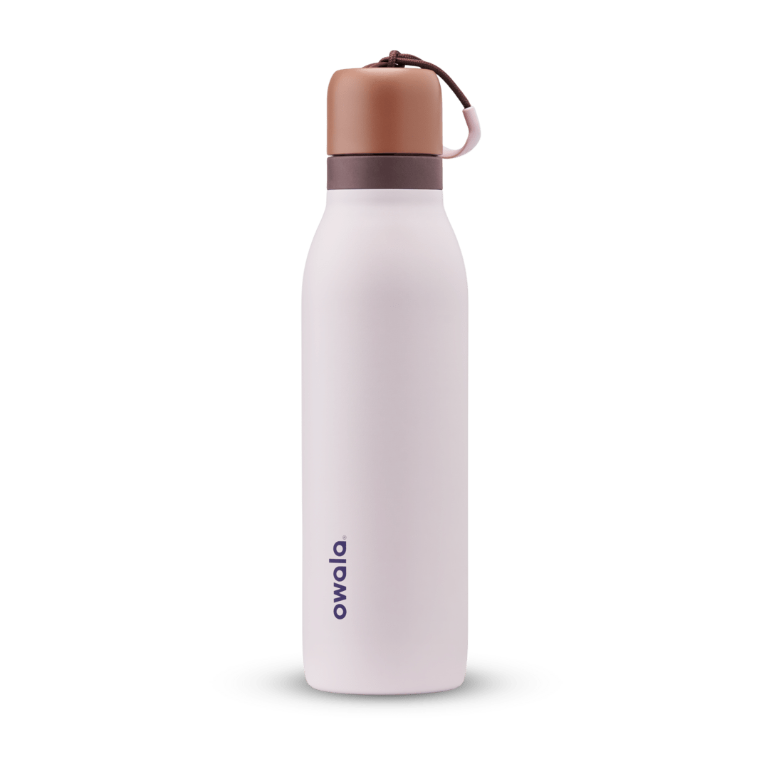 FreeSip Twist 18oz in Sleepy Lavender, soft pale lavender insulated water bottle with copper-orange twist cap, dark plum twist cap accent band, and pink carry string with brown grip